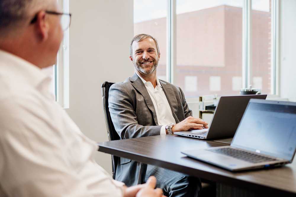 Derek Oglesby sitting at a desk with Andrew George